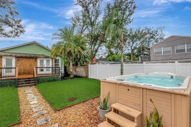 view of yard with a fenced backyard, a wooden deck, a hot tub, and french doors