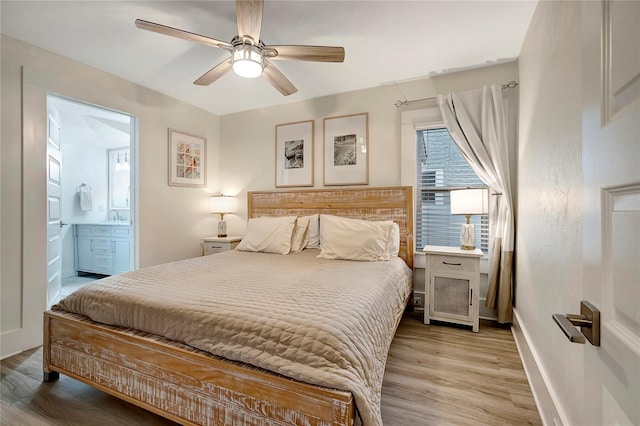 bedroom featuring light wood-type flooring, baseboards, connected bathroom, and a sink