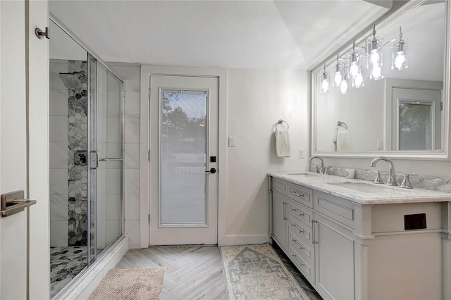 full bathroom with baseboards, a sink, a shower stall, and double vanity
