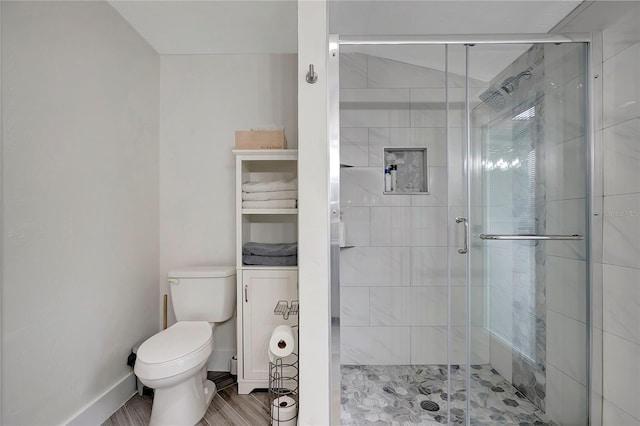 full bathroom with a stall shower, baseboards, and toilet