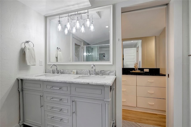 full bathroom featuring double vanity, a stall shower, wood finished floors, and a sink