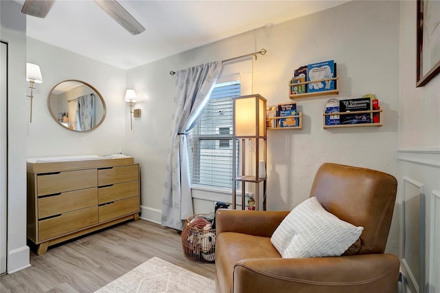 living area with baseboards, a ceiling fan, and light wood finished floors