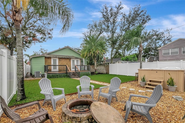 view of yard with a fire pit, a fenced backyard, central AC unit, and a deck