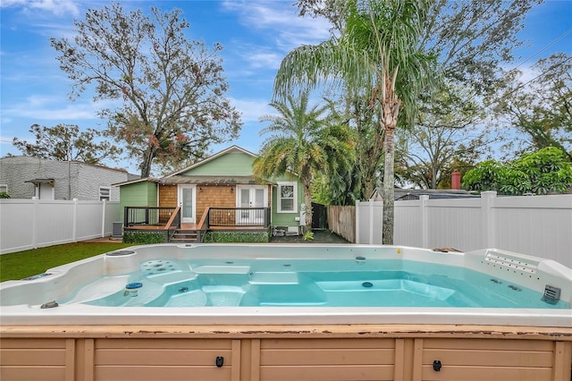 view of pool featuring a wooden deck, a fenced backyard, and a hot tub