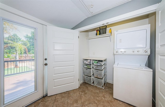 laundry room with stacked washer / drying machine, a wealth of natural light, light tile patterned floors, and laundry area