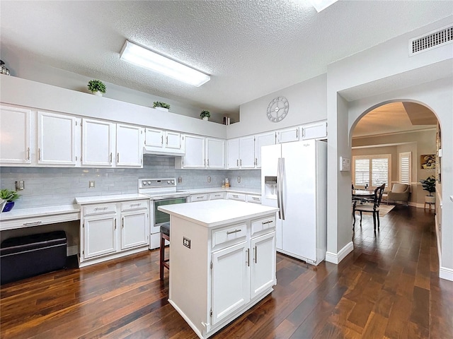 kitchen featuring white appliances, dark wood-type flooring, white cabinets, a kitchen island, and decorative backsplash