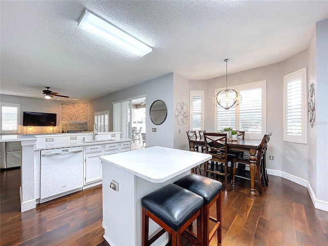 kitchen with decorative light fixtures, dishwasher, sink, white cabinets, and dark wood-type flooring