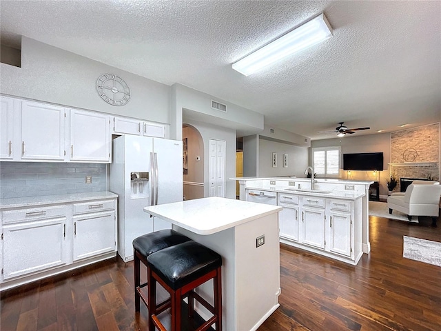 kitchen with a center island, sink, white cabinets, and white appliances