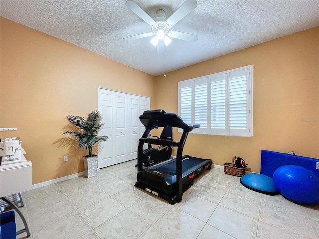 exercise room featuring ceiling fan, light tile patterned floors, and a textured ceiling