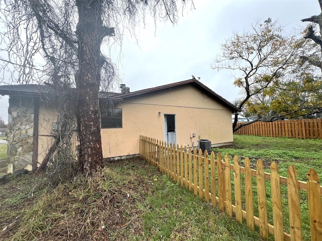 view of property exterior featuring central AC unit and a lawn