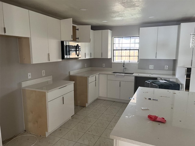 kitchen with sink, light tile patterned flooring, and white cabinetry