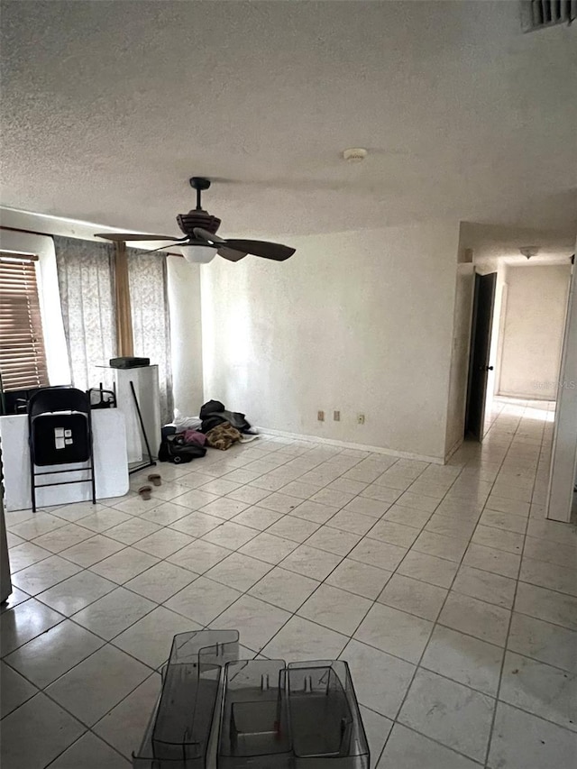 unfurnished living room with a textured ceiling, light tile patterned floors, and ceiling fan