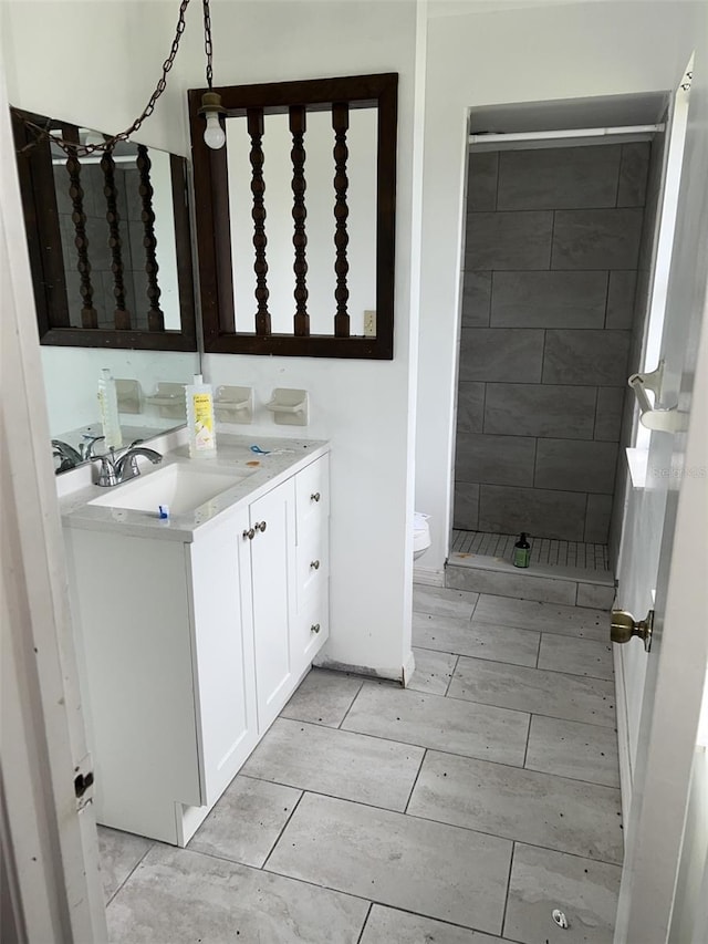 bathroom featuring a tile shower, toilet, and vanity