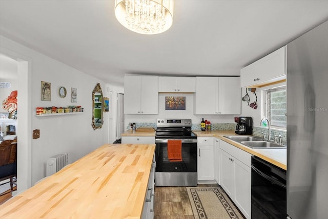 kitchen featuring sink, radiator, butcher block counters, stainless steel appliances, and white cabinets