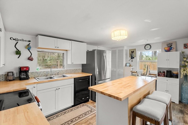 kitchen with white cabinetry, sink, dishwasher, and butcher block countertops