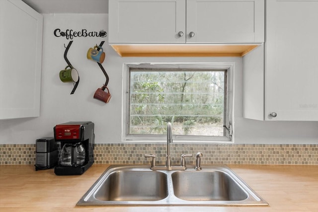 kitchen featuring tasteful backsplash, white cabinetry, and sink