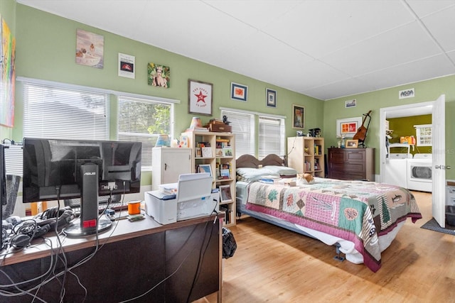 bedroom featuring washer / dryer, multiple windows, and light wood-type flooring