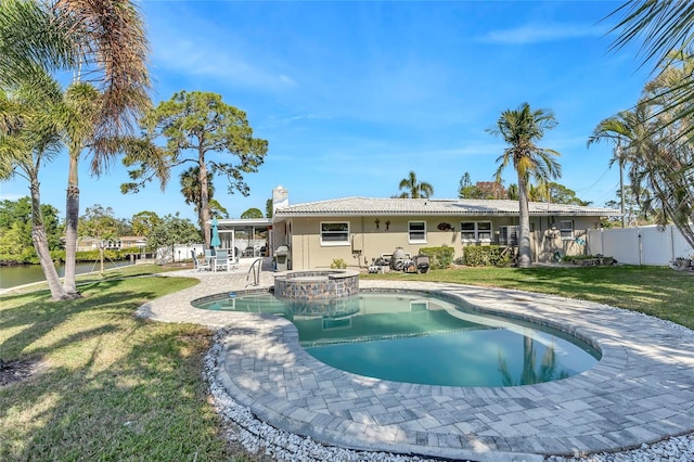 rear view of house featuring a swimming pool with hot tub, a yard, and a patio area