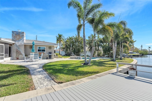 exterior space featuring a water view, a grill, a yard, and a patio area