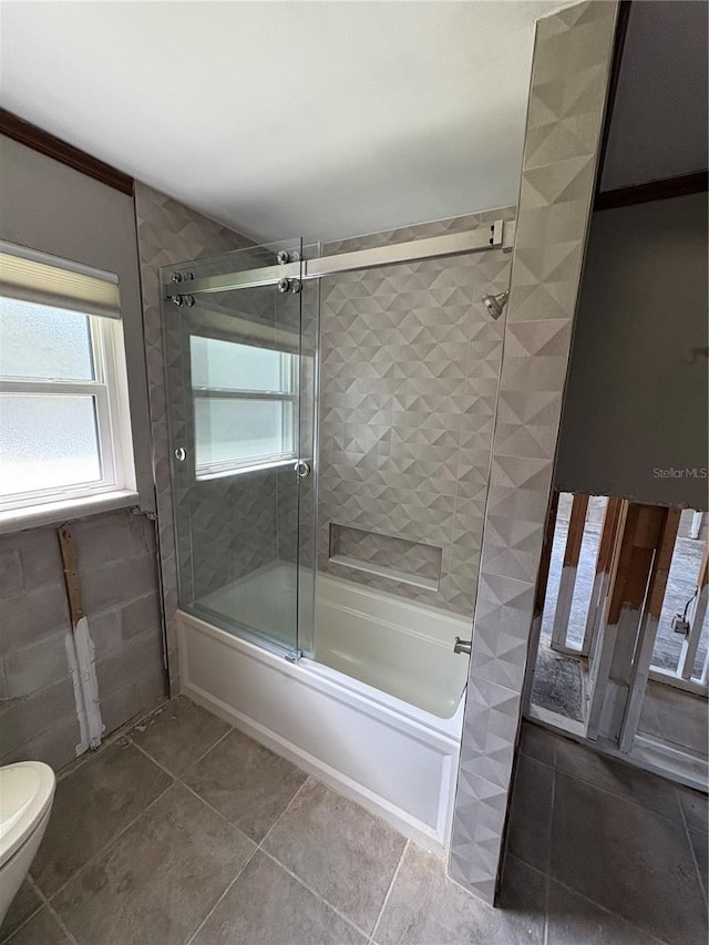 bathroom with tile patterned flooring, toilet, and combined bath / shower with glass door