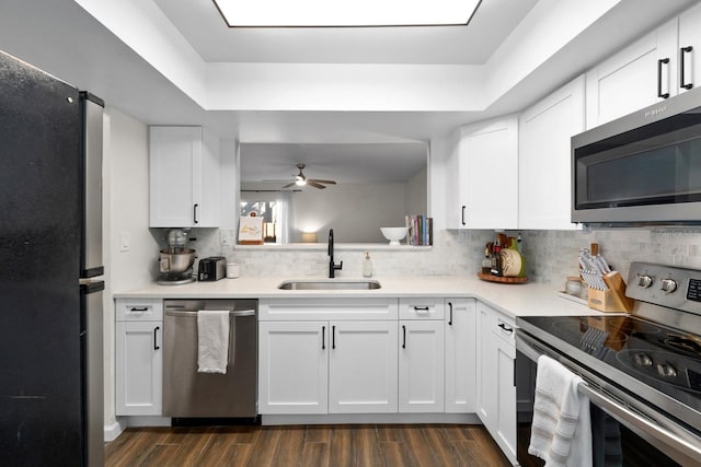 kitchen featuring sink, white cabinetry, a tray ceiling, and appliances with stainless steel finishes