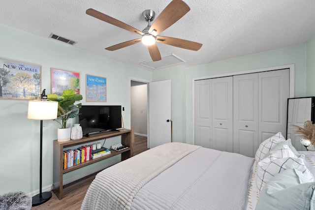 bedroom with a closet, ceiling fan, hardwood / wood-style floors, and a textured ceiling