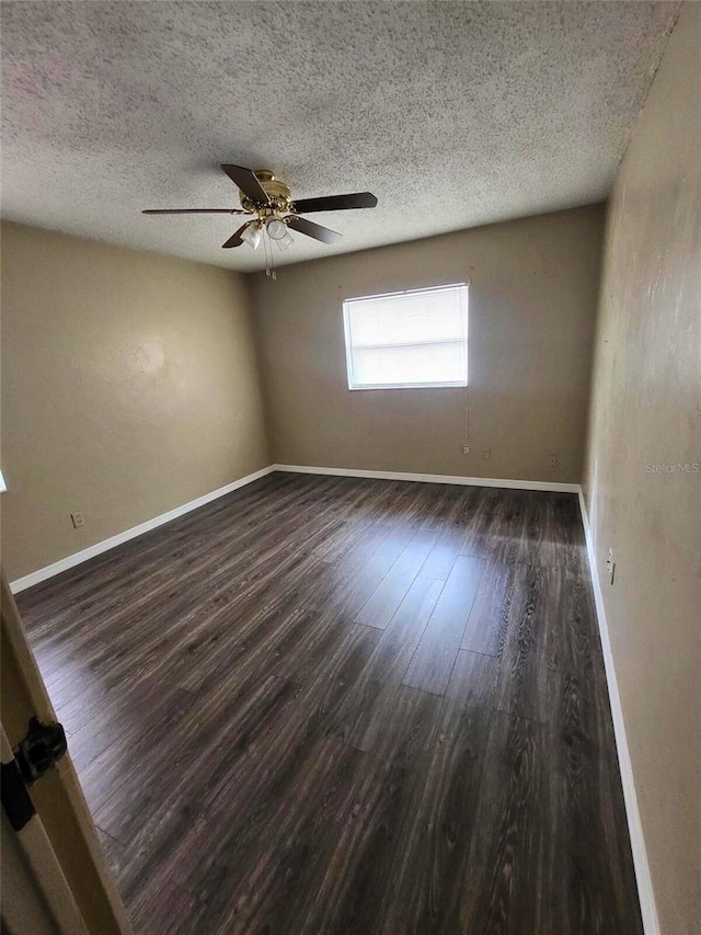 spare room with ceiling fan, dark wood-type flooring, and a textured ceiling