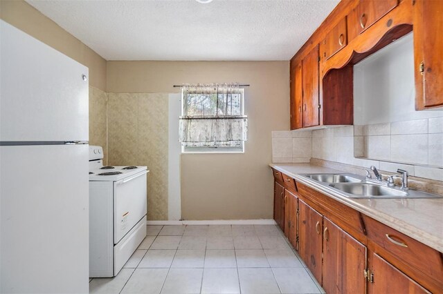 5130 Dr Martin Luther King Jr St S, Saint Petersburg, FL 33705 - kitchen with a sink, white appliances, brown cabinetry, light countertops, and decorative backsplash