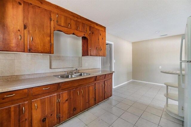 5130 Dr Martin Luther King Jr St S, Saint Petersburg, FL 33705 - kitchen featuring light tile patterned flooring, freestanding refrigerator, a sink, light countertops, and backsplash