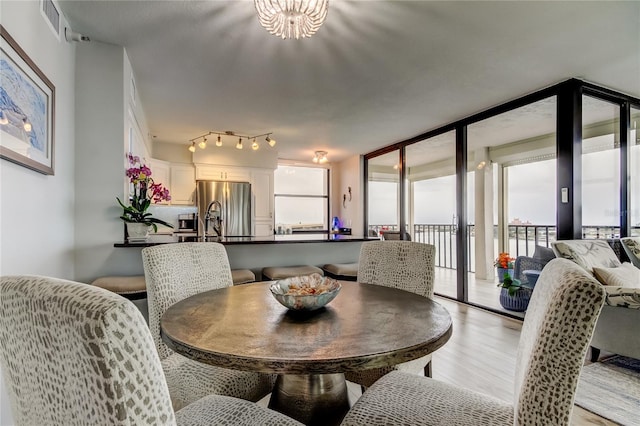 dining space with an inviting chandelier, a wall of windows, and light hardwood / wood-style floors