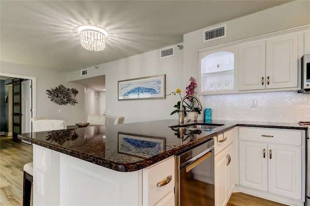 kitchen featuring white cabinetry, sink, dark stone counters, and kitchen peninsula