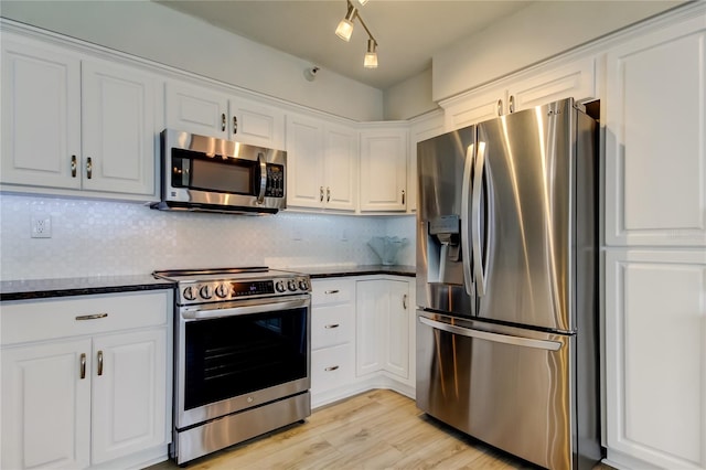 kitchen with tasteful backsplash, appliances with stainless steel finishes, light wood-type flooring, and white cabinets