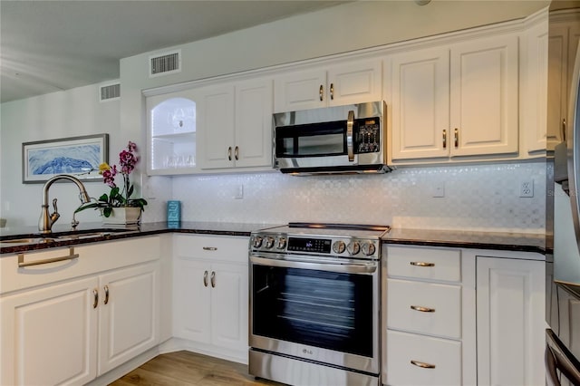 kitchen with stainless steel appliances, white cabinetry, sink, and tasteful backsplash