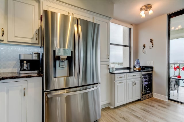 kitchen featuring wine cooler, white cabinetry, light hardwood / wood-style flooring, stainless steel fridge, and decorative backsplash