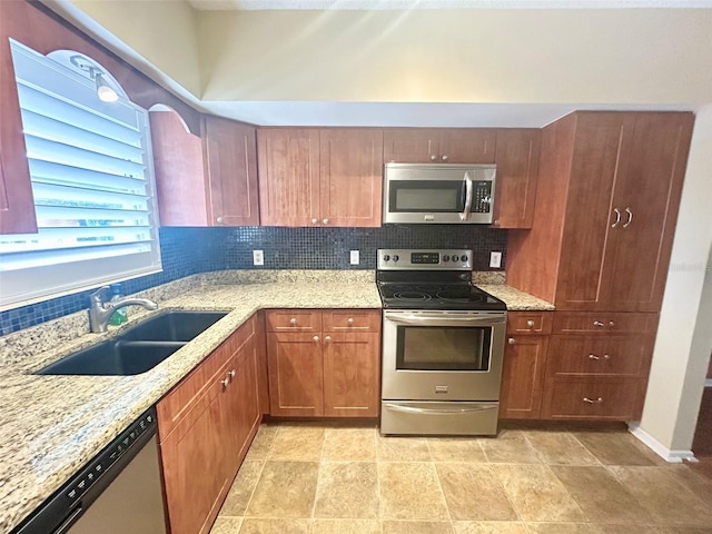 kitchen with sink, stainless steel appliances, light stone countertops, and tasteful backsplash