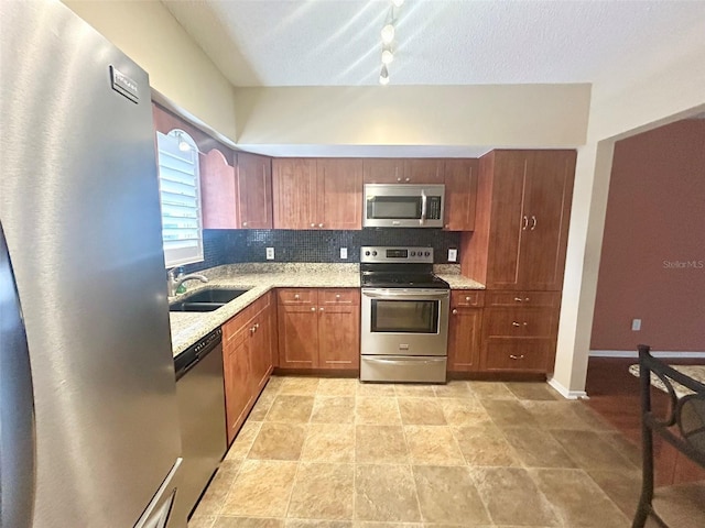 kitchen with sink, light stone counters, appliances with stainless steel finishes, and tasteful backsplash