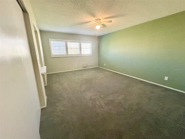 unfurnished room with a ceiling fan, baseboards, dark carpet, and a textured ceiling