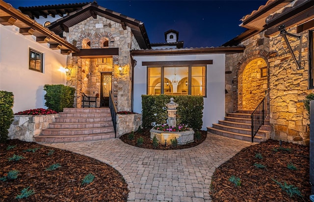 exterior entry at twilight with stone siding and stucco siding