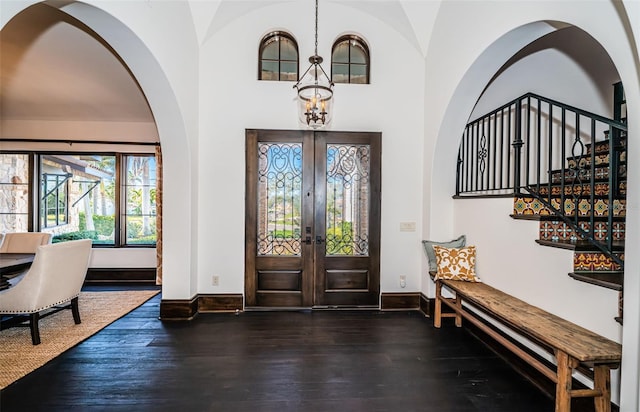 entrance foyer featuring baseboards, dark wood-style floors, an inviting chandelier, stairs, and french doors