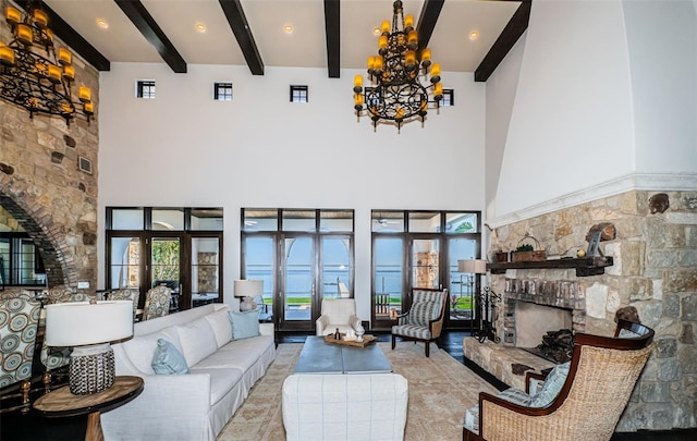 living area with an inviting chandelier, a high ceiling, a fireplace with raised hearth, and beam ceiling