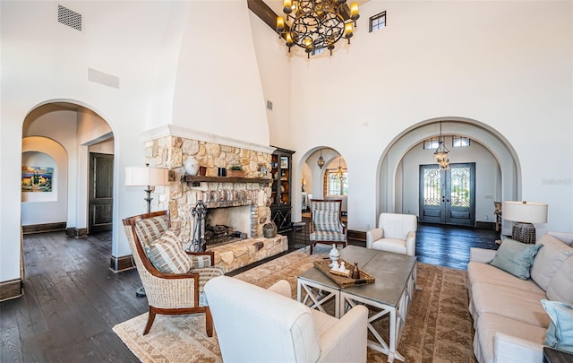 living room with dark wood-style floors, a fireplace, arched walkways, and french doors