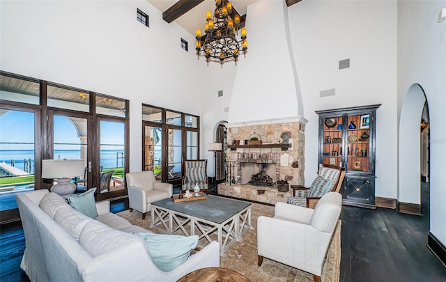 living room featuring a fireplace, a water view, visible vents, dark wood-style floors, and beamed ceiling