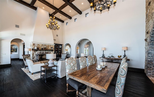 dining area with visible vents, arched walkways, dark wood-style flooring, an inviting chandelier, and a fireplace