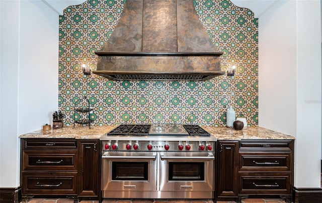 kitchen featuring range with two ovens, light stone counters, dark brown cabinetry, tasteful backsplash, and custom range hood