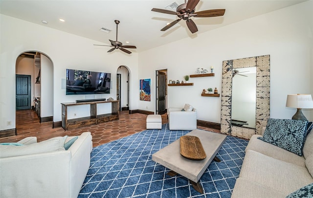 living room featuring arched walkways, visible vents, dark tile patterned floors, and baseboards