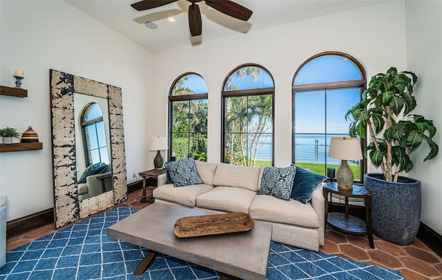 living area featuring a water view, baseboards, and a ceiling fan