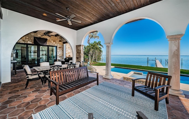 view of patio featuring outdoor dining area, outdoor lounge area, a water view, a ceiling fan, and a hot tub