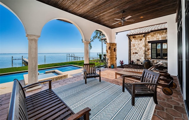 view of patio featuring an in ground hot tub, a water view, a ceiling fan, and an outdoor pool