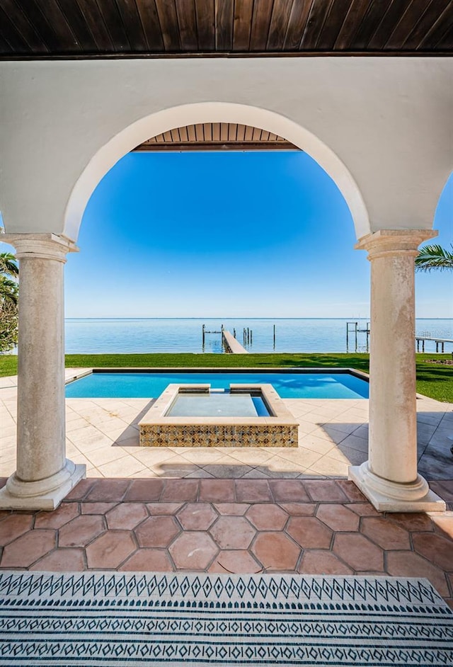 outdoor pool featuring a water view, a patio, and an in ground hot tub