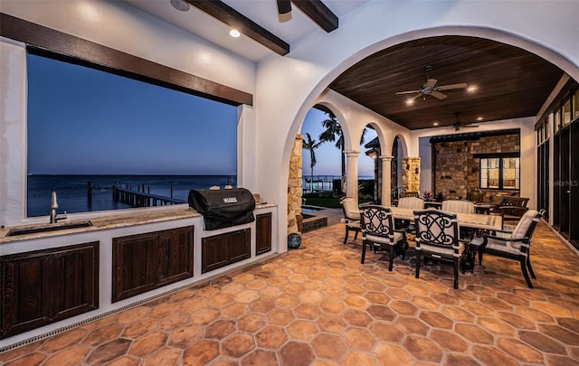 view of patio with ceiling fan, outdoor dining area, a water view, a sink, and grilling area